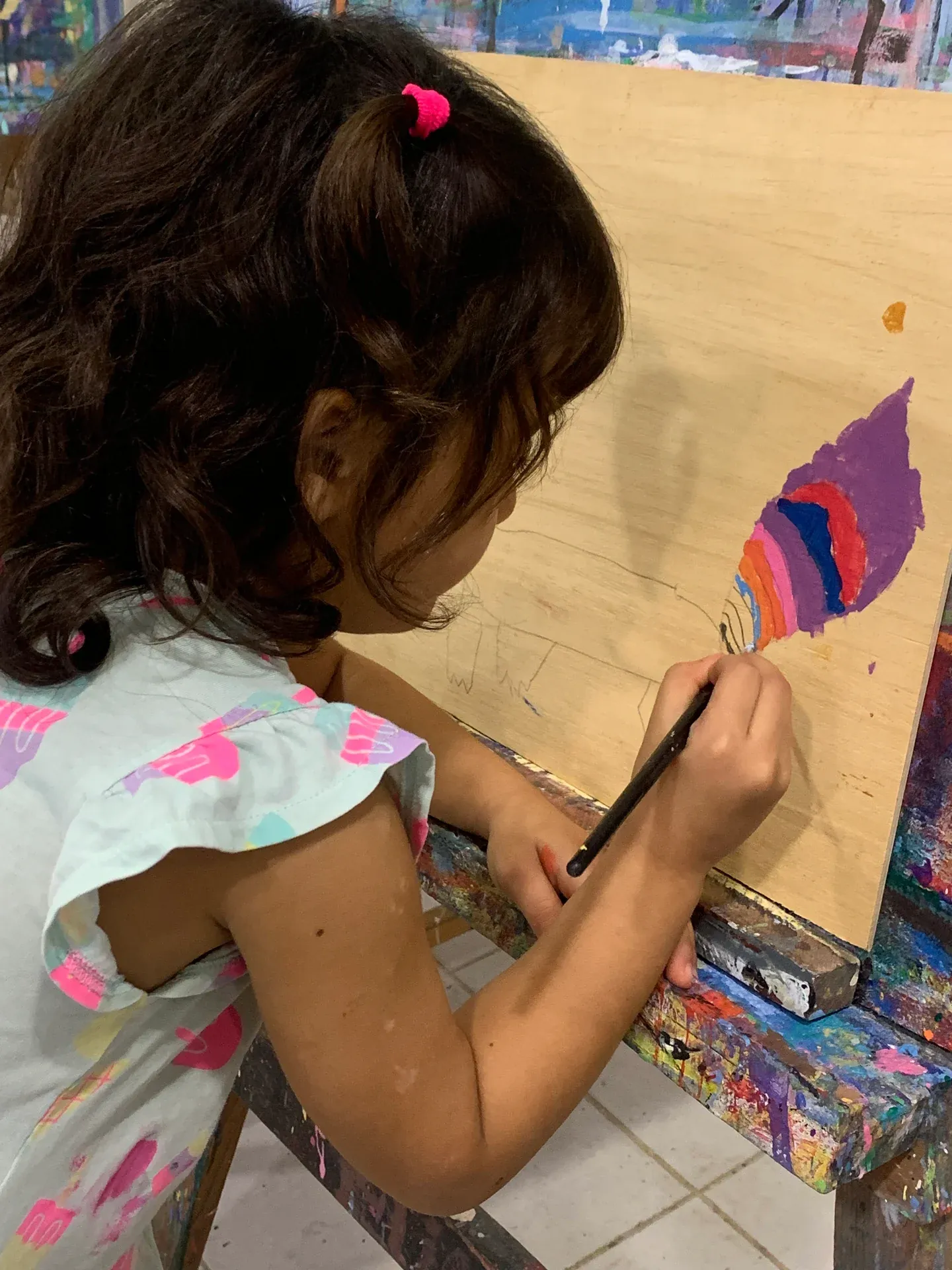 Young girl drawing and painting at her easel